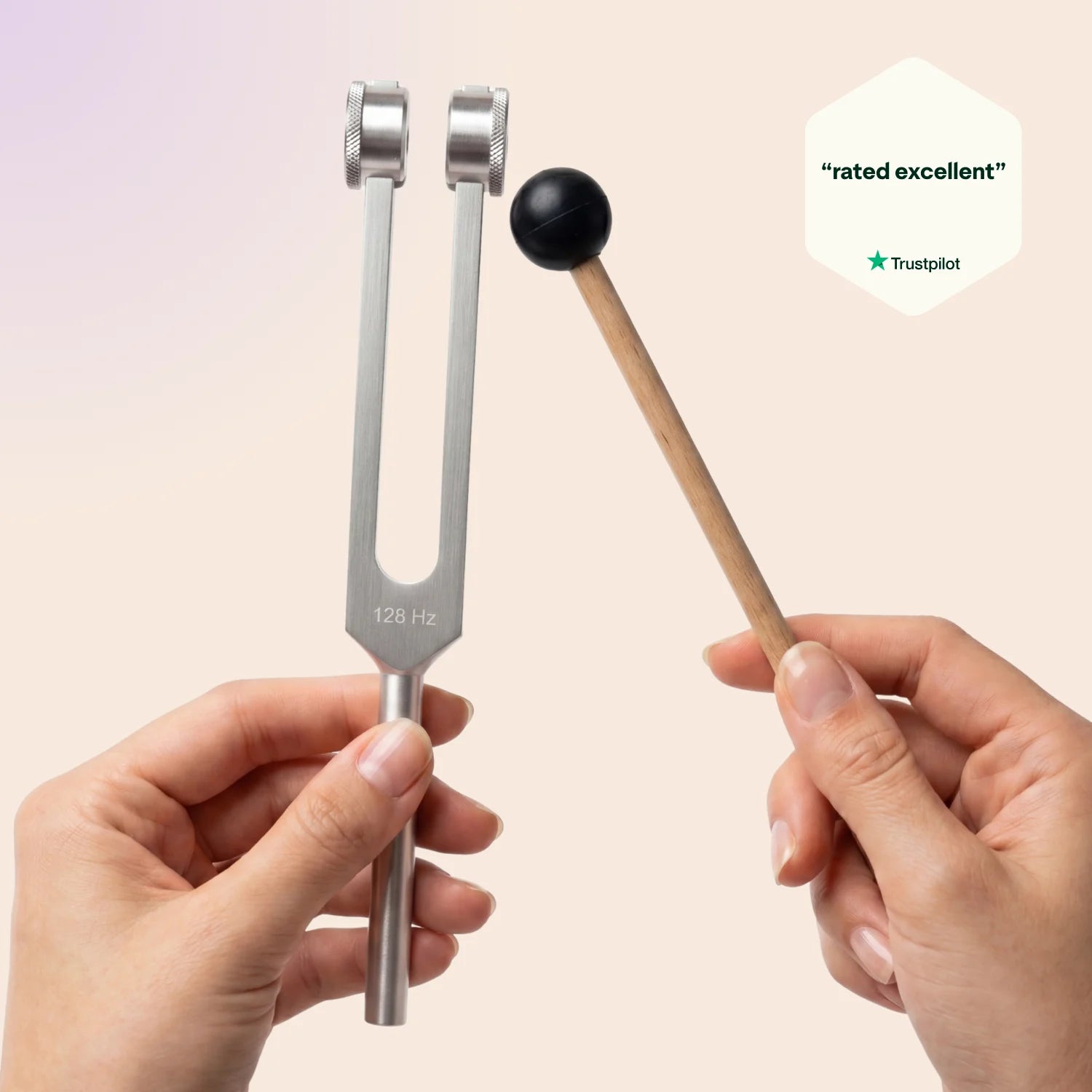 128 Hz tuning fork held by a hand with a black mallet, on a beige background with Trustpilot rating.