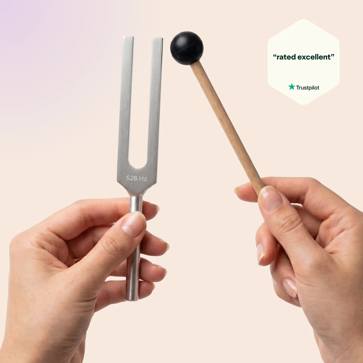 528 Hz tuning fork held by a hand with a mallet, on a beige background, featuring Trustpilot rating.