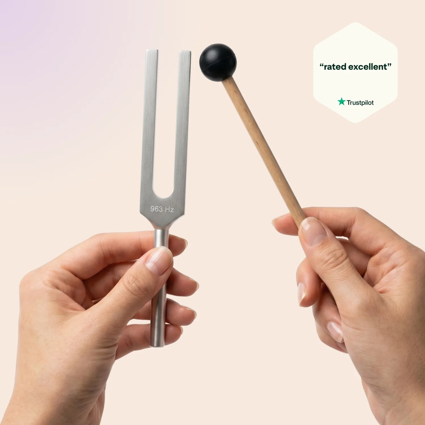 963 Hz tuning fork held by a hand with a mallet, on a light pink background, featuring Trustpilot rating.