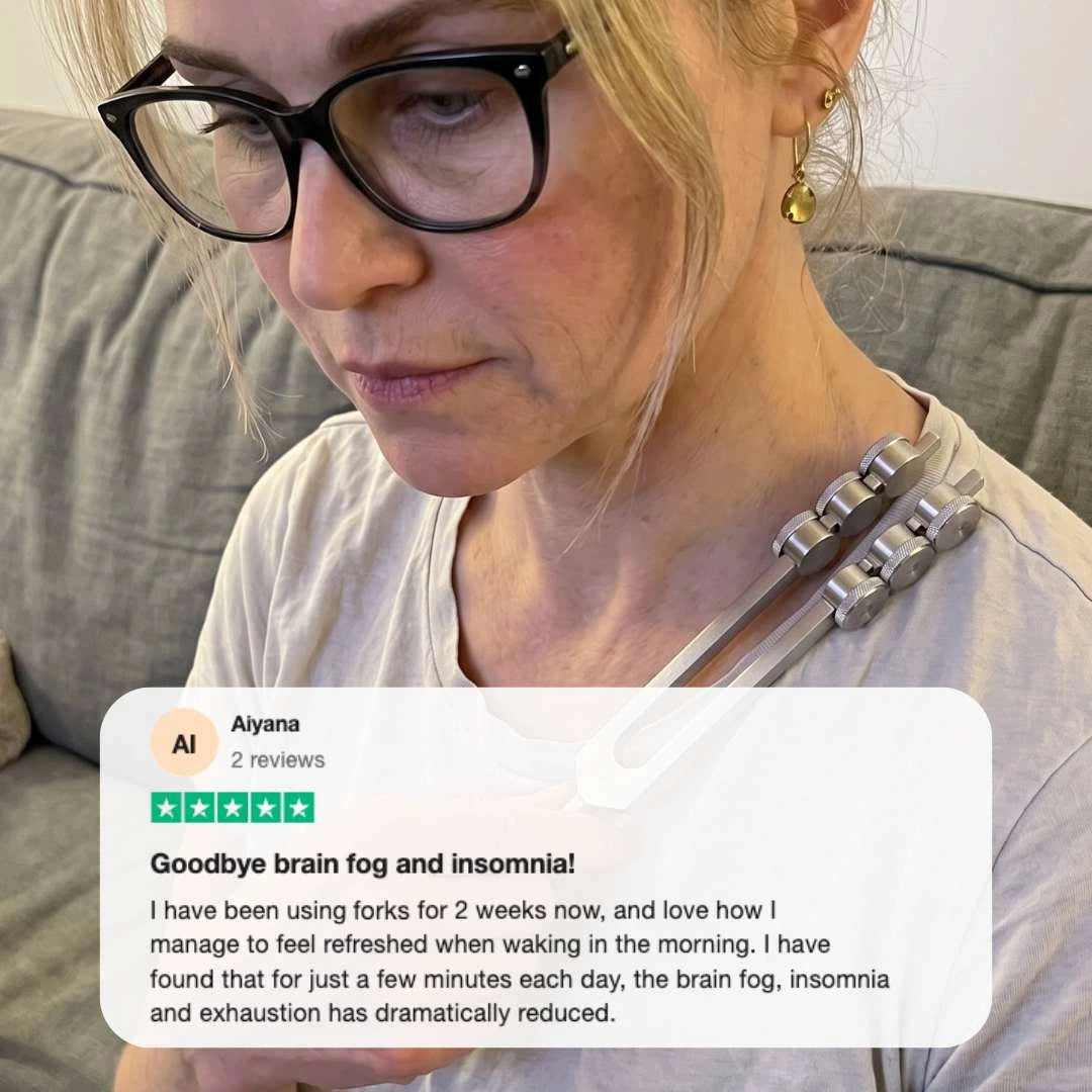 Woman using 32 Hz weighted tuning fork near ear for deep relaxation and nervous system reset