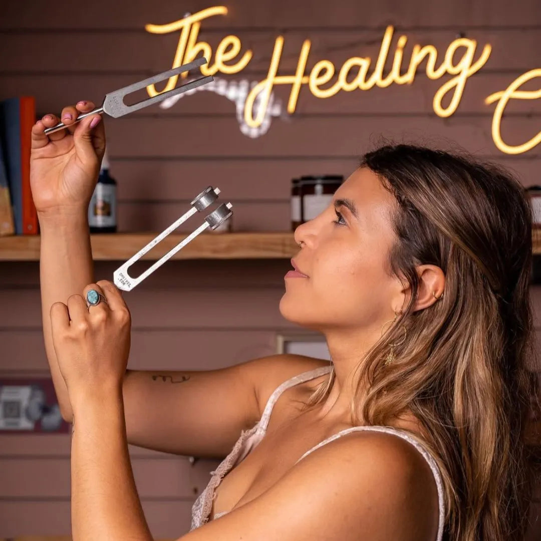 Woman holding tuning forks near her face during a sound healing session